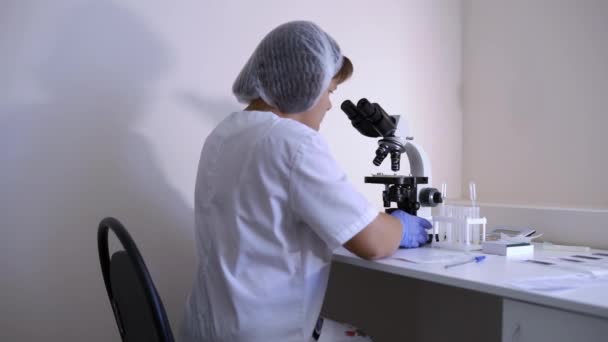 Mulher técnica de laboratório entra para se sentar em seu laboratório de trabalho para teste de vírus de trabalho — Vídeo de Stock