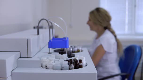 Operator of the biochemical analyzer coronavirus, a woman is not in focus, closeup side view. — Stock Video