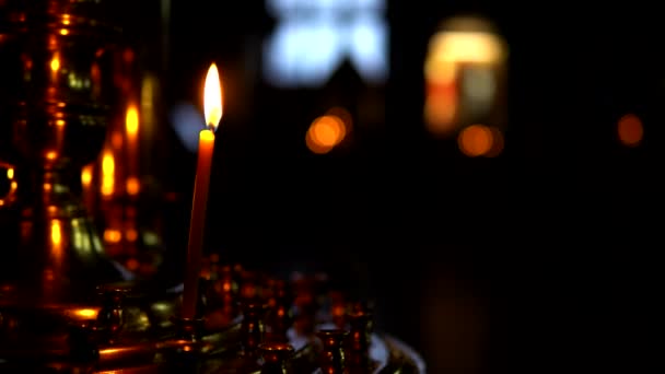 Une bougie allumée dans un grand chandelier en or dans la pièce sombre de l'église orthodoxe — Video