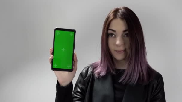 Портрет женщины со смартфоном с зеленым экраном в руке, которая звонит, чтобы посмотреть на него — стоковое видео