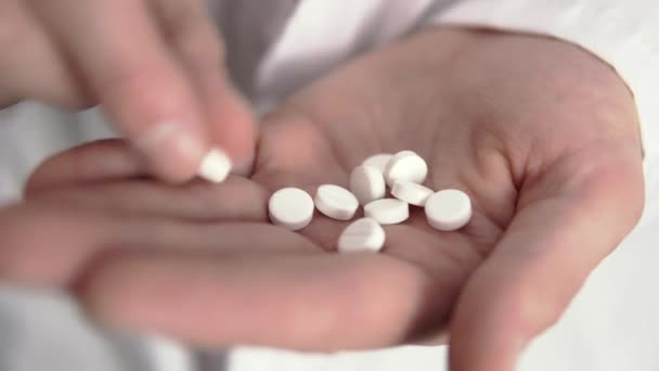 Un médico está contando pastillas blancas en su mano en primer plano — Vídeo de stock