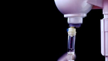 Doktor damlalık sistemi kuruyor ve şırıngayla siyah arka planda ilaç enjekte ediyor.