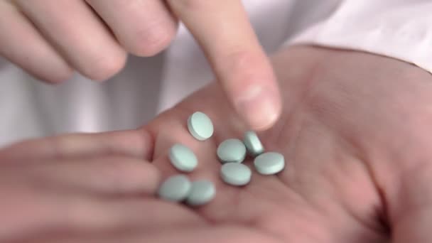 Close-up van Kaukasische artsen hand die is het tellen van blauwe pillen door zijn vinger — Stockvideo