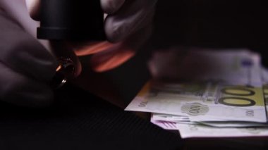 Altın yüzüğü yakından büyüterek değerlendiren bir rehinci sahibinin elleri.