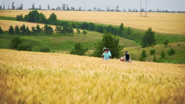 Kaukasische Familie läuft in Zeitlupe weit weg auf einem Sommerweizenfeld — Stockvideo