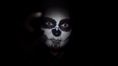 Santa Muerte tarzında esrarengiz bir kadın siyah arka planda yakın planda.