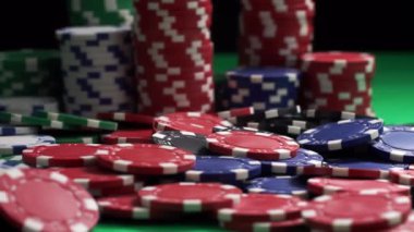 Çok renkli bir poker fişi yığını yakın planda yeşil bir masanın üzerinde duruyor.