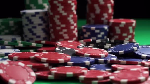 Куча разноцветных фишек для покера лежит на зеленом столе крупным планом — стоковое видео
