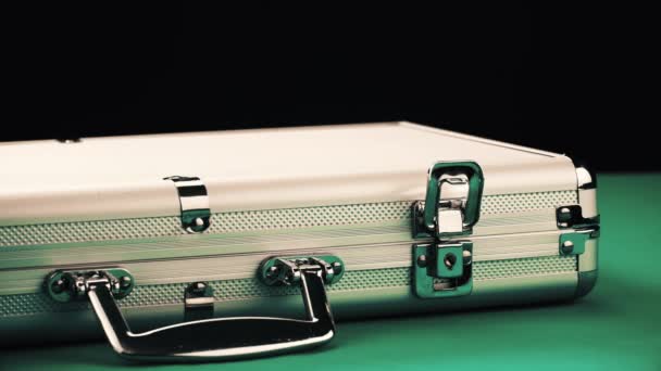 Opening a metal suitcase with poker equipment on a green table and black background — Stock Video