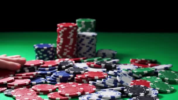 La mano cuenta fichas de póquer acostado en una mesa verde sobre un fondo negro en primer plano — Vídeos de Stock