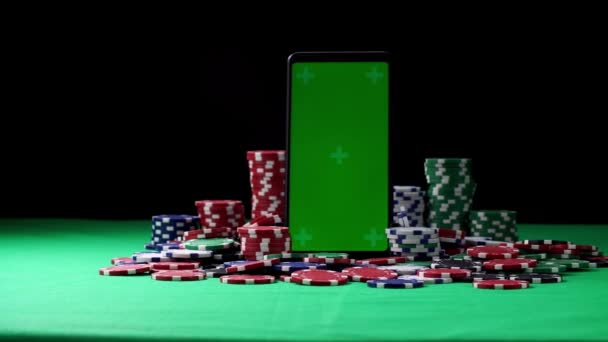 Zelená obrazovka smartphone ve vertikální orientaci uprostřed pokerových žetonů — Stock video