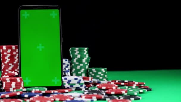 Крупный план мобильного телефона с хрома-ключом в вертикальной ориентации среди кучи фишек для покера — стоковое видео