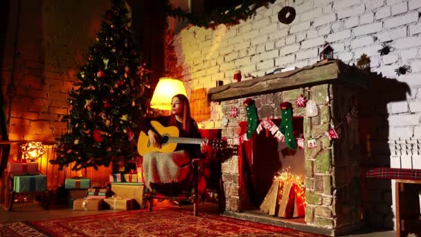 Παίζοντας κιθάρα και τραγουδώντας ένα γιο νεαρή κοπέλα γιορτάζει την Πρωτοχρονιά σε ένα όμορφο εσωτερικό — Αρχείο Βίντεο