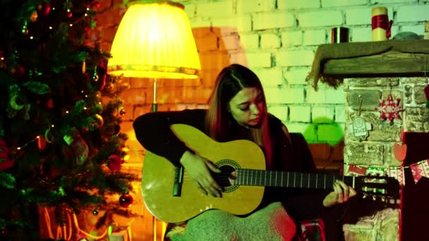 Porträt einer kaukasischen Frau, die in Neujahrsatmosphäre Gitarre spielt und ihren Sohn singt — Stockvideo
