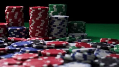 Yığınla renkli poker çipleri yakın planda yeşil masanın üzerinde duruyor.