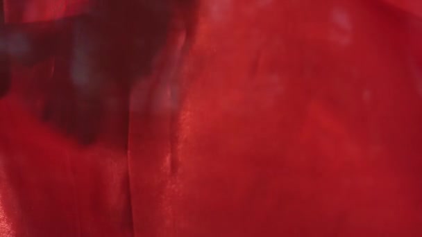 Rood glanzend textiel trilt op een wind in close-up en slow motion — Stockvideo