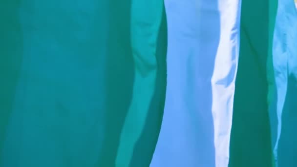 Veelkleurige zijde groene en blauwe vlaggen zwaaien op een wind in slowmo — Stockvideo