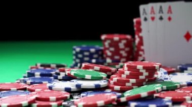 Bir yığın poker fişi ve aralarında yeşil bir masada yatan dört as.