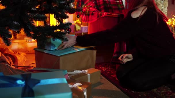 Primer plano de la joven caucásica poniendo regalos bajo el árbol de Navidad decorado — Vídeos de Stock