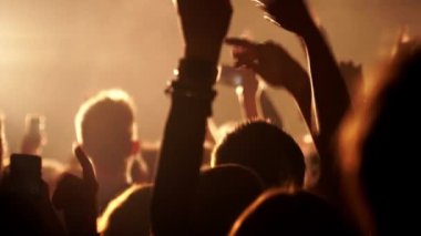 Dans eden kalabalık ellerini ağır çekimde müzik konserinde kaldırdı.