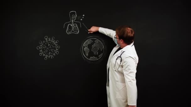 Vědec v lékařské masce stojí na tabuli a vysvětluje, jak se covid-19 šíří — Stock video