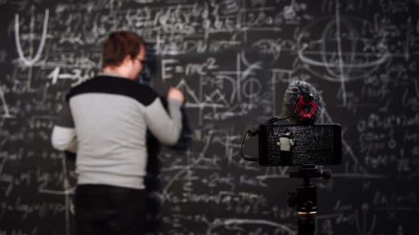 Professor draws triangle and proves theorem standing at blackboard in front of smartphone camera — Stock Video