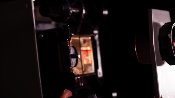 Tampilan makro dari proyektor geser vintage dan jari-jari yang memutar roda untuk memindahkan film dengan gambar — Stok Video