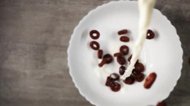 Yukardan yavaş çekimde akan sütle dolu bir kase çikolata.