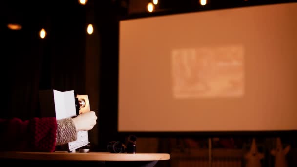 Dáma ukazuje diapozitivy na plátně s pomocí retro projektoru stojícího na stole — Stock video