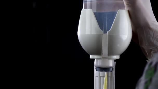 Close-up de uma mão enfermeiros colocando uma agulha no sistema de infusão no fundo preto em slowmo — Vídeo de Stock