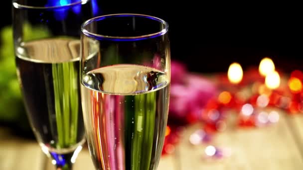 Twee wijnglazen met champagne aan tafel op wazige kaars lichte bokeh achtergrond — Stockvideo