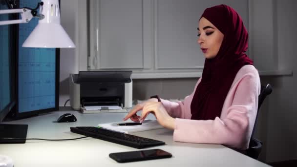 Женщина-мусульманский менеджер говорит по видеокассетам и показывает документ с графиком после того, как напечатала его — стоковое видео