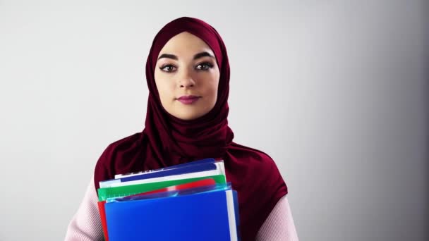 Vereinzeltes Porträt einer muslimischen Studentin mit Ordnern auf weißem Hintergrund — Stockvideo