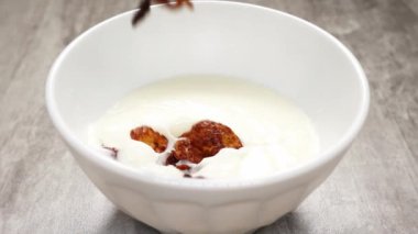 Çikolata aromalı mısır gevrekleri yukarıdan yavaş yavaş süt dolu beyaz bir tabağa uçuyor.