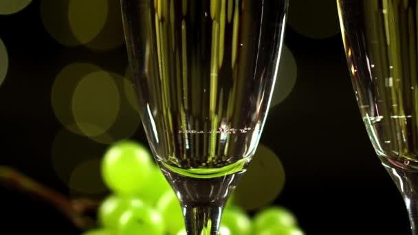 Macro view of two glasses full of sparkling wine against illumination background — Stock Video