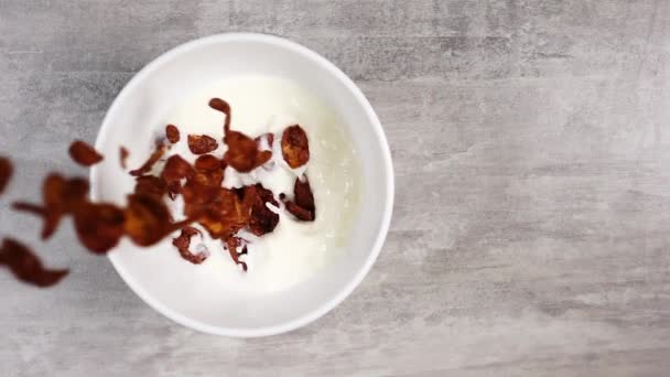 Widok z góry wylewanie płatków kukurydzianych o smaku czekolady do białej miski z mlekiem w zwolnionym tempie — Wideo stockowe