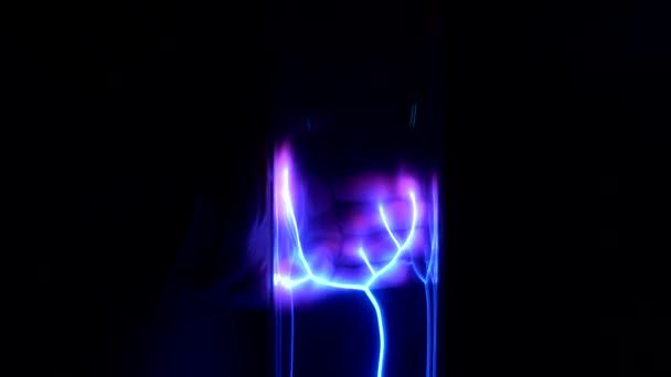 Nahaufnahme der Hand, die eine Plasmalampe mit neonelektrischen Strahlen auf dem schwarzen Hintergrund berührt — Stockvideo