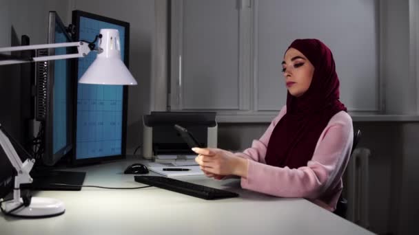 当有人用智能手机给她打电话时，这位穆斯林女士在办公室里工作 — 图库视频影像