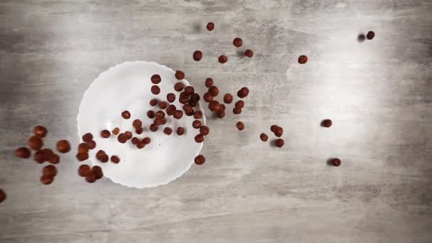 以小球形式掉下来的巧克力玉米片被倒入盘子里，倒在桌子上 — 图库视频影像