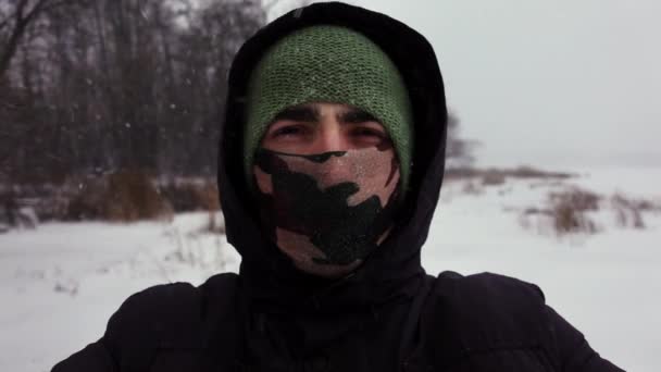 Selfie de joven con capucha y bufanda cubriendo su cara que cierra los ojos por la nieve — Vídeos de Stock