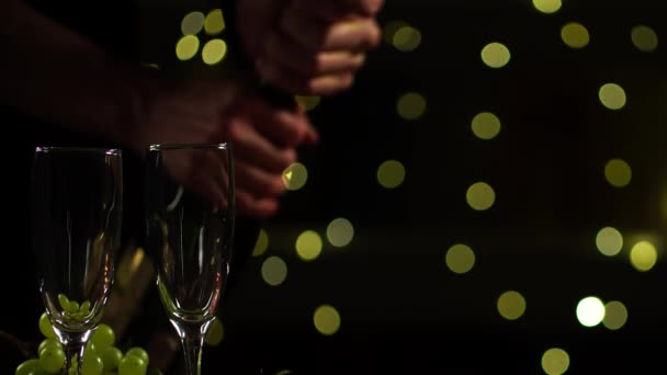 Crop view of mans handen openen fles champagne en gieten in twee wijnglazen — Stockvideo