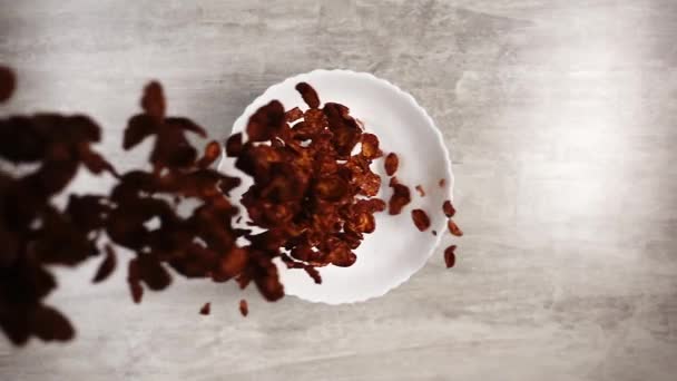 초콜릿 콘 플레이크 천천히 흰 접시에 튀기는 모습 — 비디오