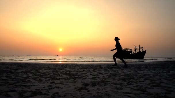 Sylwetka młodej kobiety biegającej i skaczącej po plaży — Wideo stockowe
