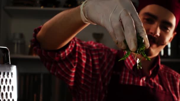Cuisinier souriant dans une toque rouge saupoudrer de persil frais pendant qu'il prépare le dîner au ralenti — Video