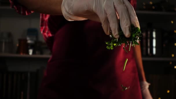Kok is garnering van een maaltijd door verse gesneden peterselie gooien met een hand in de handschoen in slow motion — Stockvideo