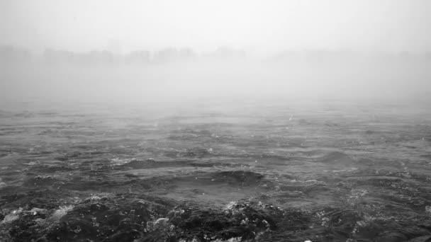 Kabbelend water in een rivier tussen vallende sneeuwvlokken en mist erboven gefilmd in slowmo — Stockvideo