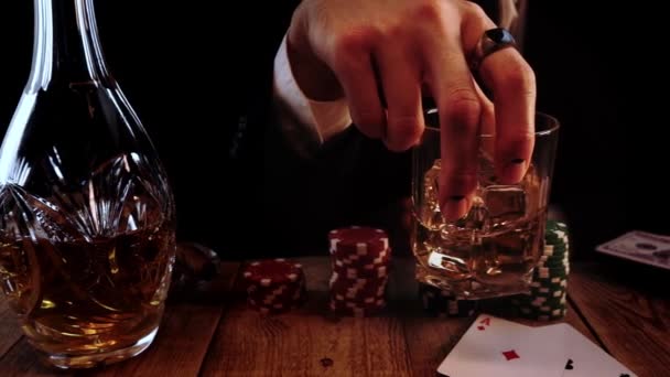Detailní pohled na muže držícího sklenici whisky s ledem a míchajícího ji během pokeru ve zpomaleném tempu — Stock video
