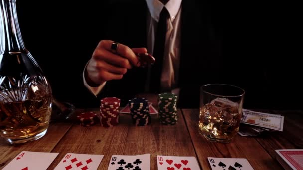 Un homme riche en costume noir jette des jetons de poker assis à la table où il y a des cartes — Video