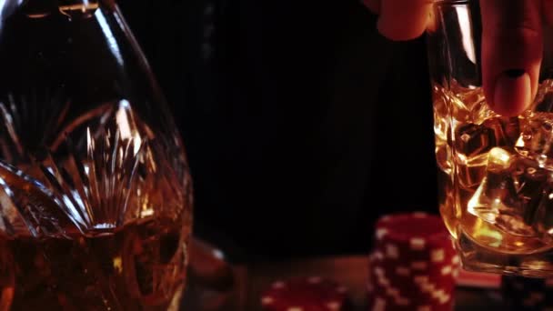 Makro záběry muže s manikúrou, který drží sklenici plnou whisky s ledem a mísí ji — Stock video