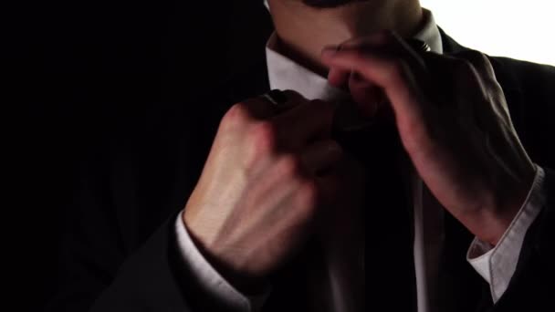 En kaukasier i svart elegant kostym justerar sin slips i makro. — Stockvideo